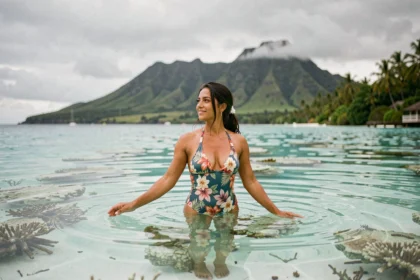 Femme polynésienne nageant dans le lagon turquoise de Tahiti avec les montagnes volcaniques en arrière-plan